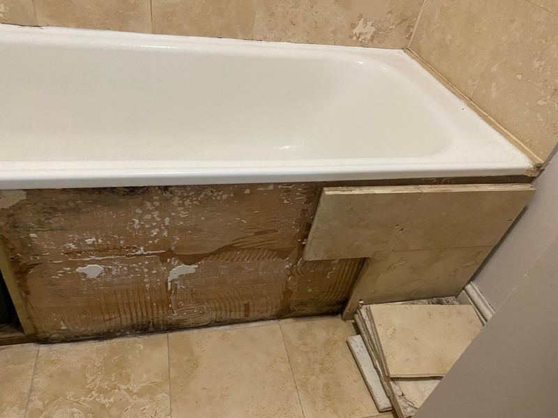 Water-damaged bath panel before repair by Magico Plumbing And Heating in Hampstead